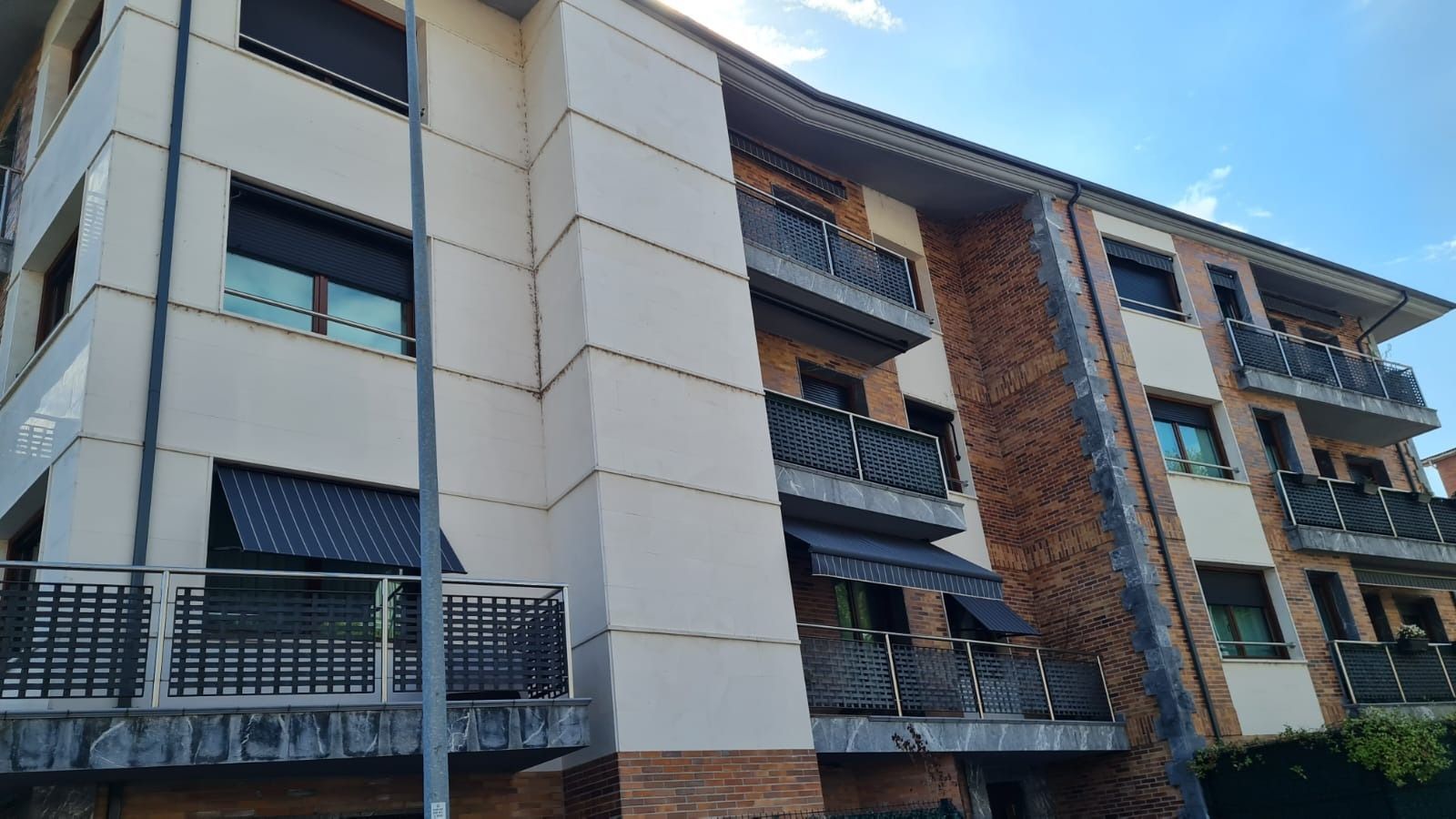 Un gran edificio de apartamentos con balcones y persianas en las ventanas.
