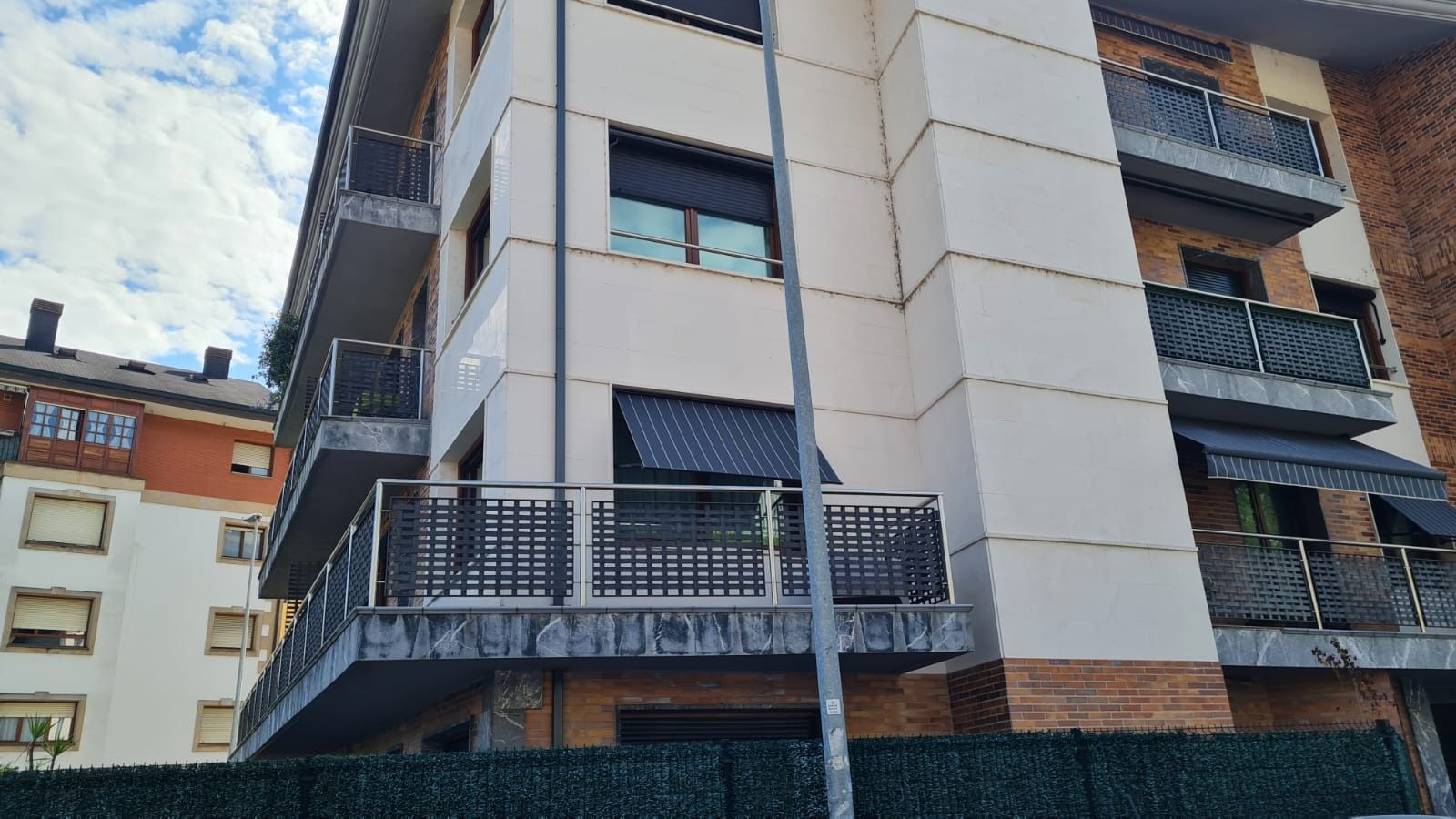 Un gran edificio de apartamentos con balcones y una valla en el frente.