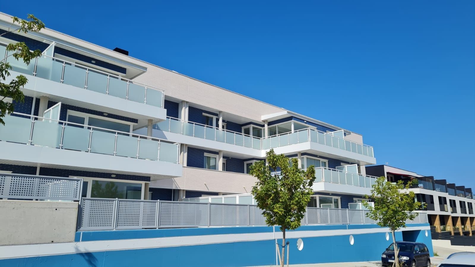 Un edificio grande con muchos balcones y un coche aparcado delante.