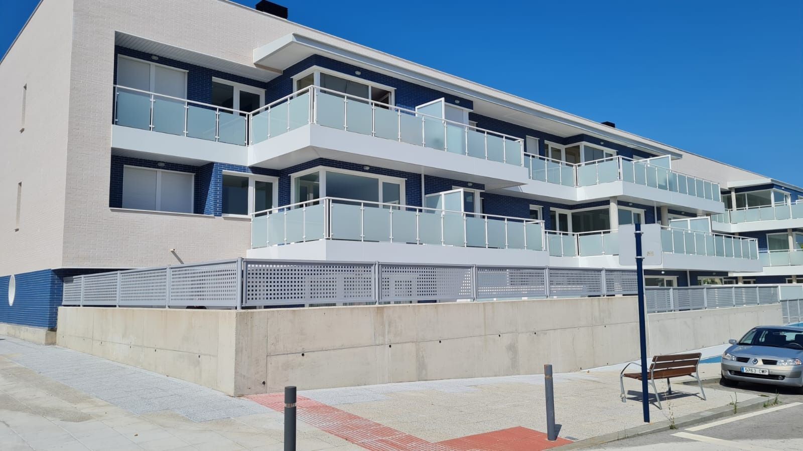 Un edificio con muchos balcones y un coche aparcado delante.