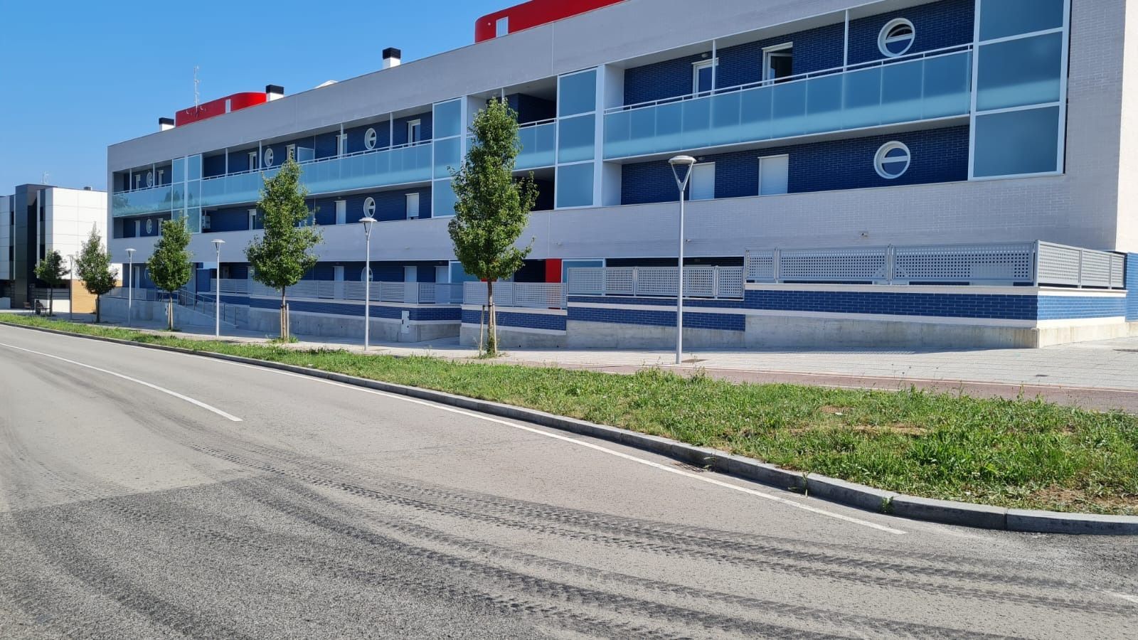 Un gran edificio con muchas ventanas está al lado de una carretera.
