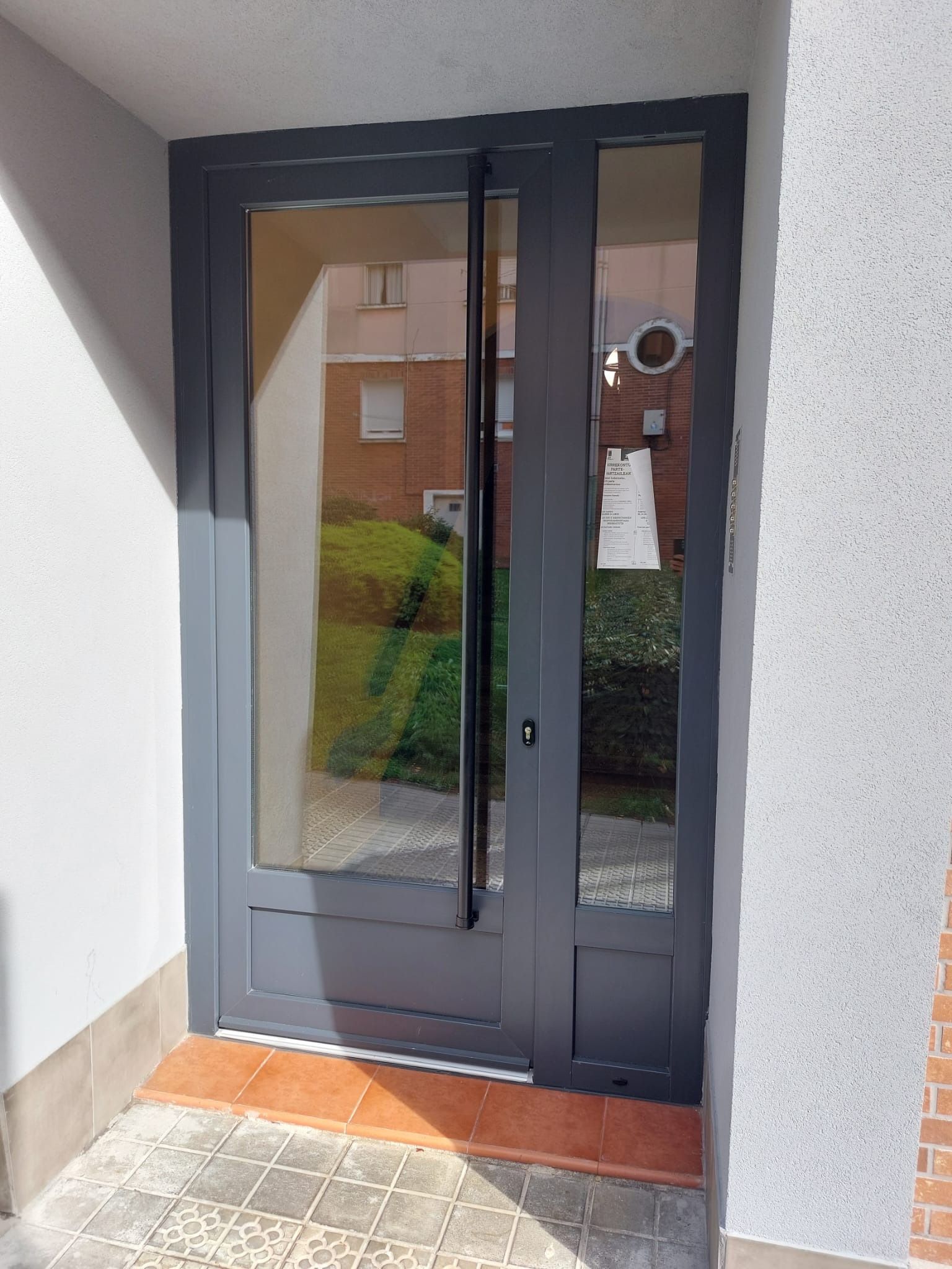 Una puerta gris con mucho vidrio.