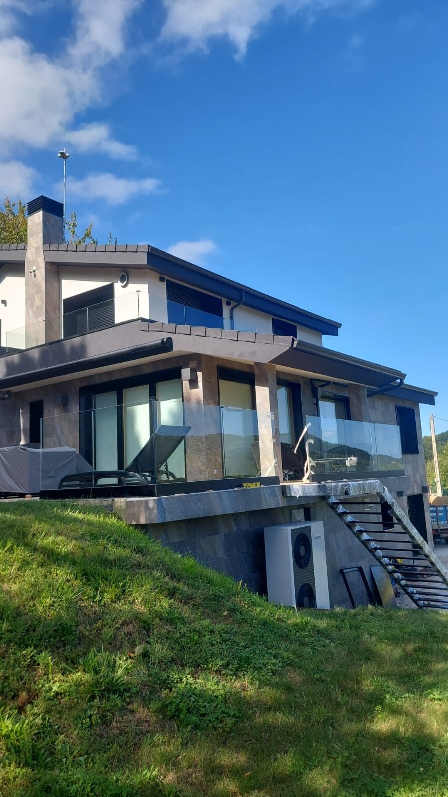 Una casa grande está situada en la cima de una colina cubierta de hierba.