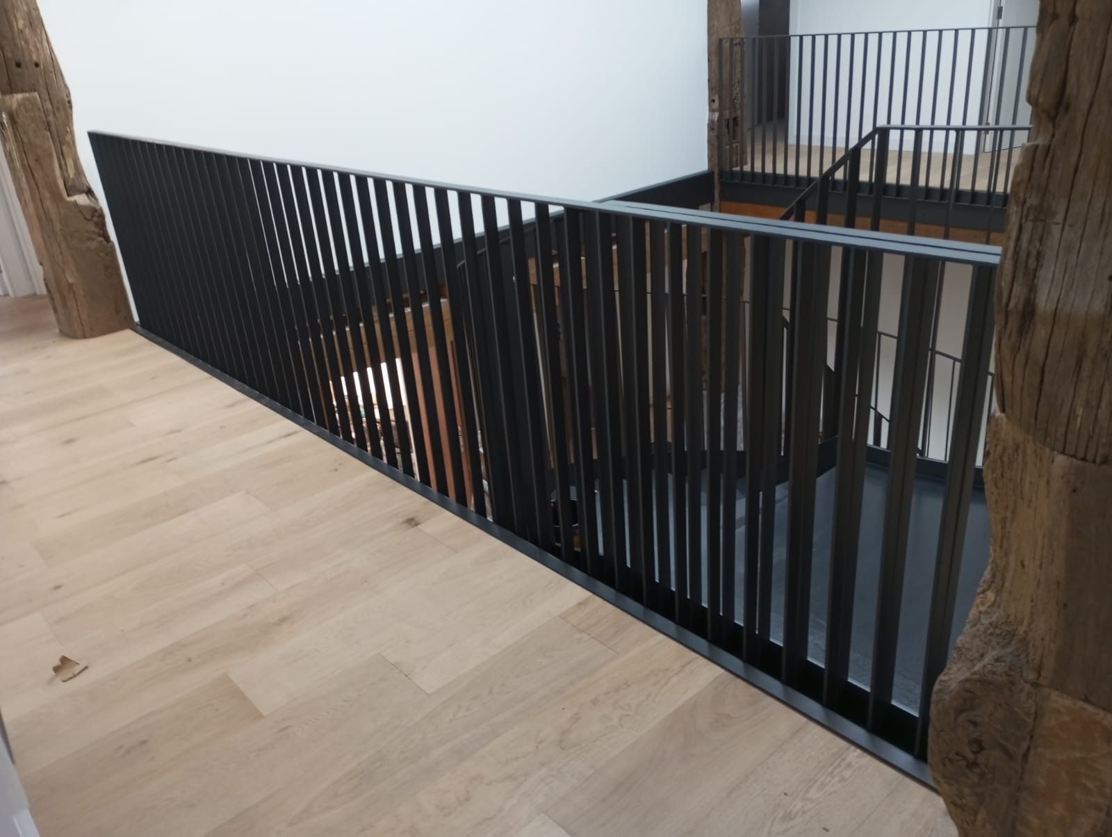 Una escalera con barandilla negra y suelo de madera.