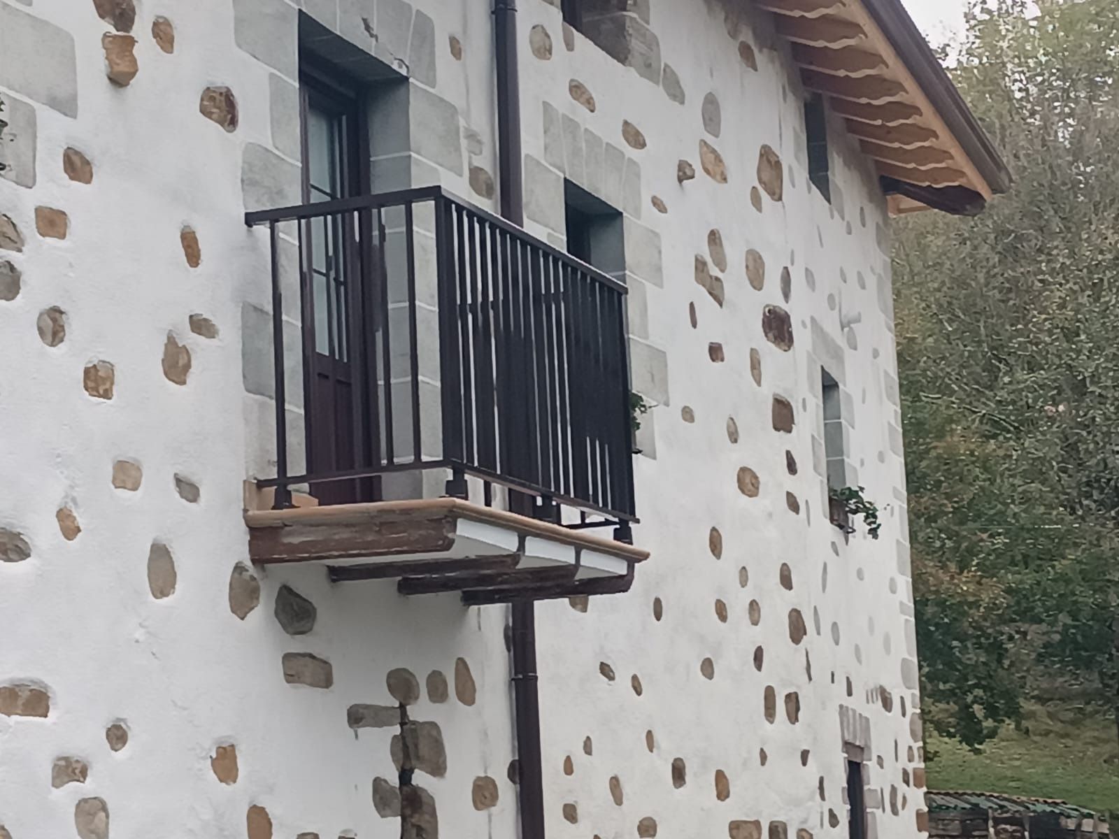 Un edificio blanco con un balcón al costado.