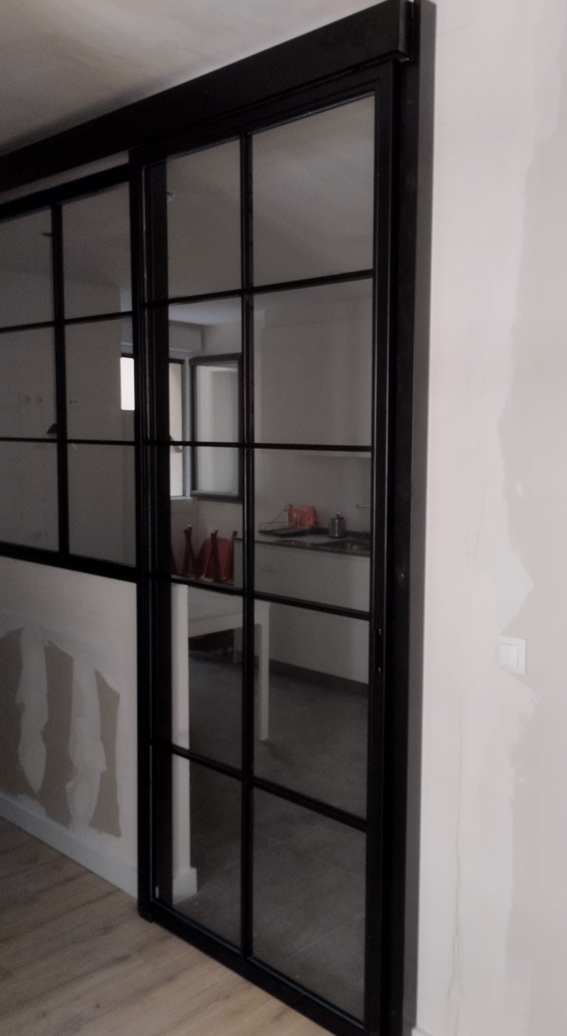 Una puerta corrediza de vidrio en una habitación con una cocina al fondo.