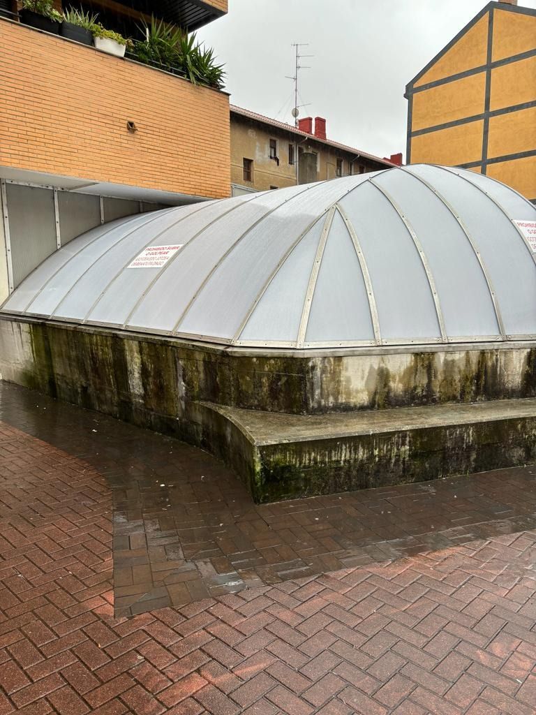 Una gran estructura en forma de cúpula se encuentra sobre una acera de ladrillo frente a un edificio.