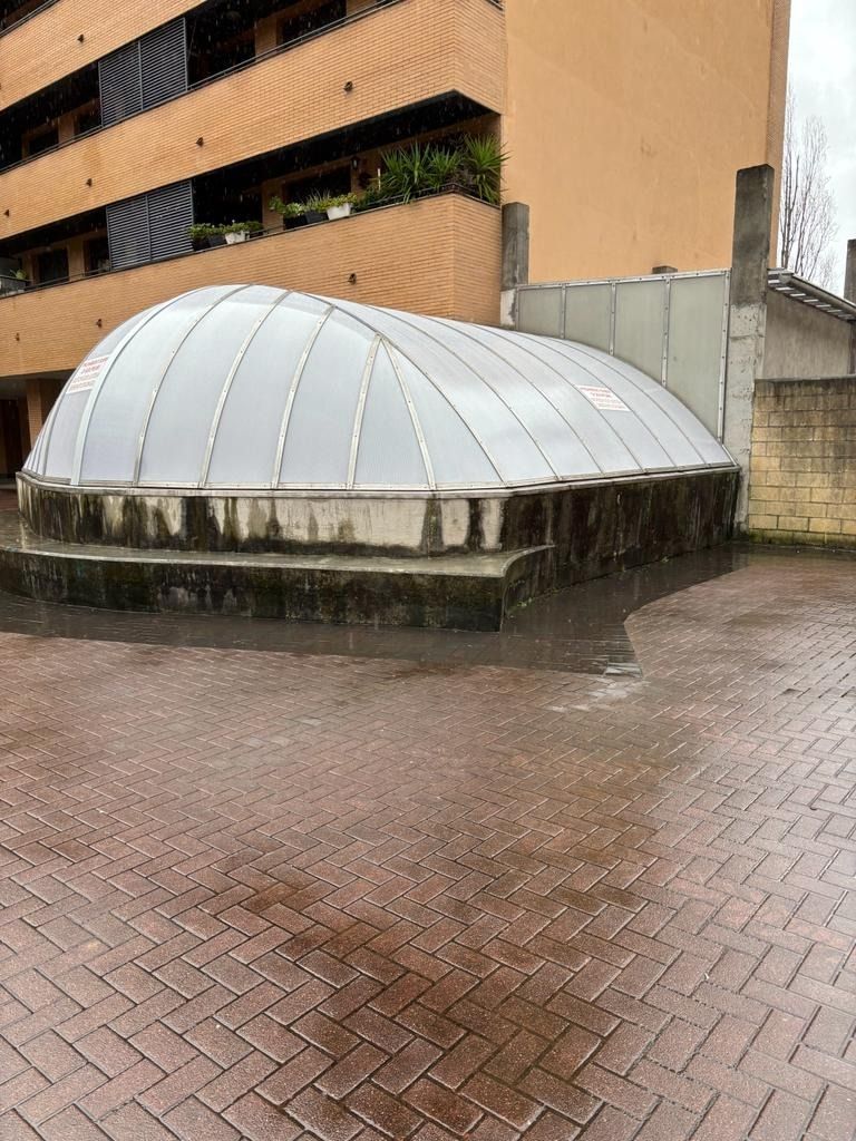 Una gran estructura en forma de cúpula se encuentra sobre una acera de ladrillo frente a un edificio.