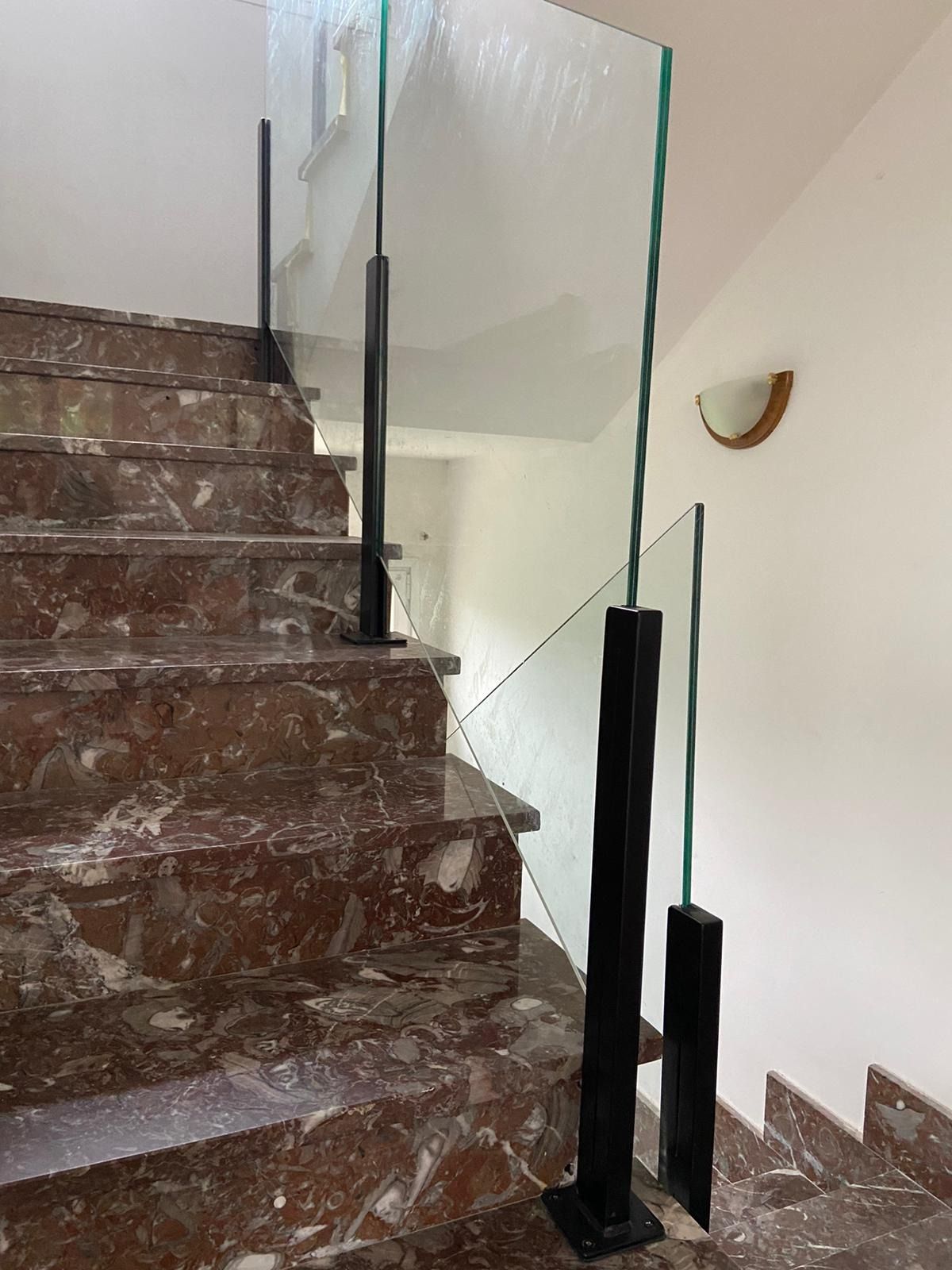 Una escalera con escalones de mármol y barandilla de cristal.