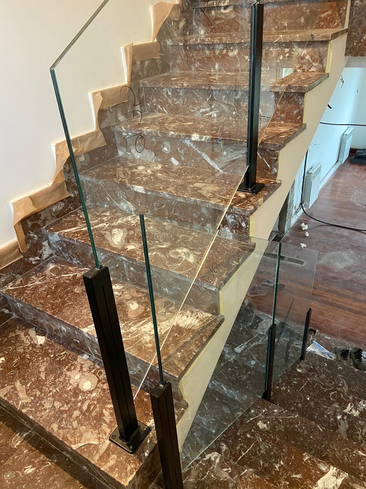 Una escalera con escalones de mármol y barandilla de cristal.