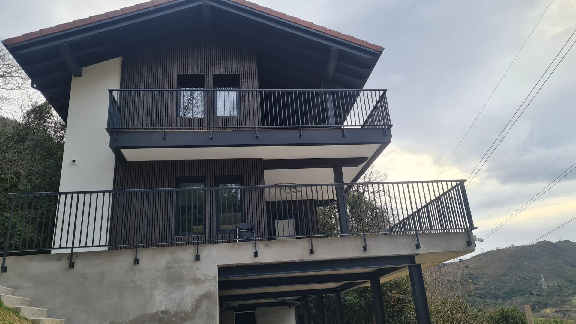 Una casa con balcón y escaleras al costado del mismo.