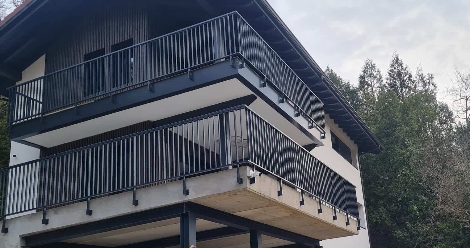 Una casa grande con balcón y barandilla negra.