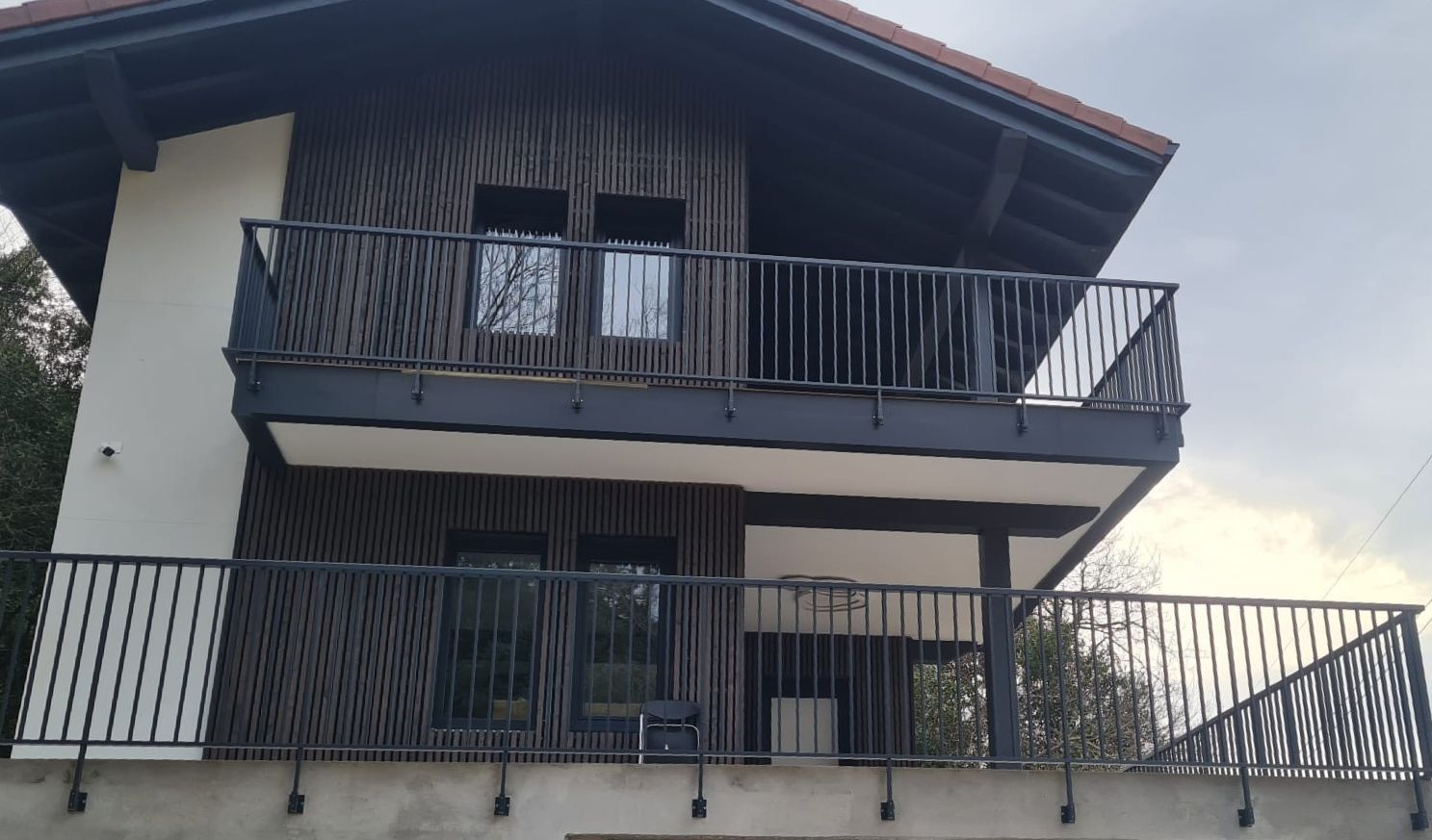 Una casa con balcón y barandilla negra