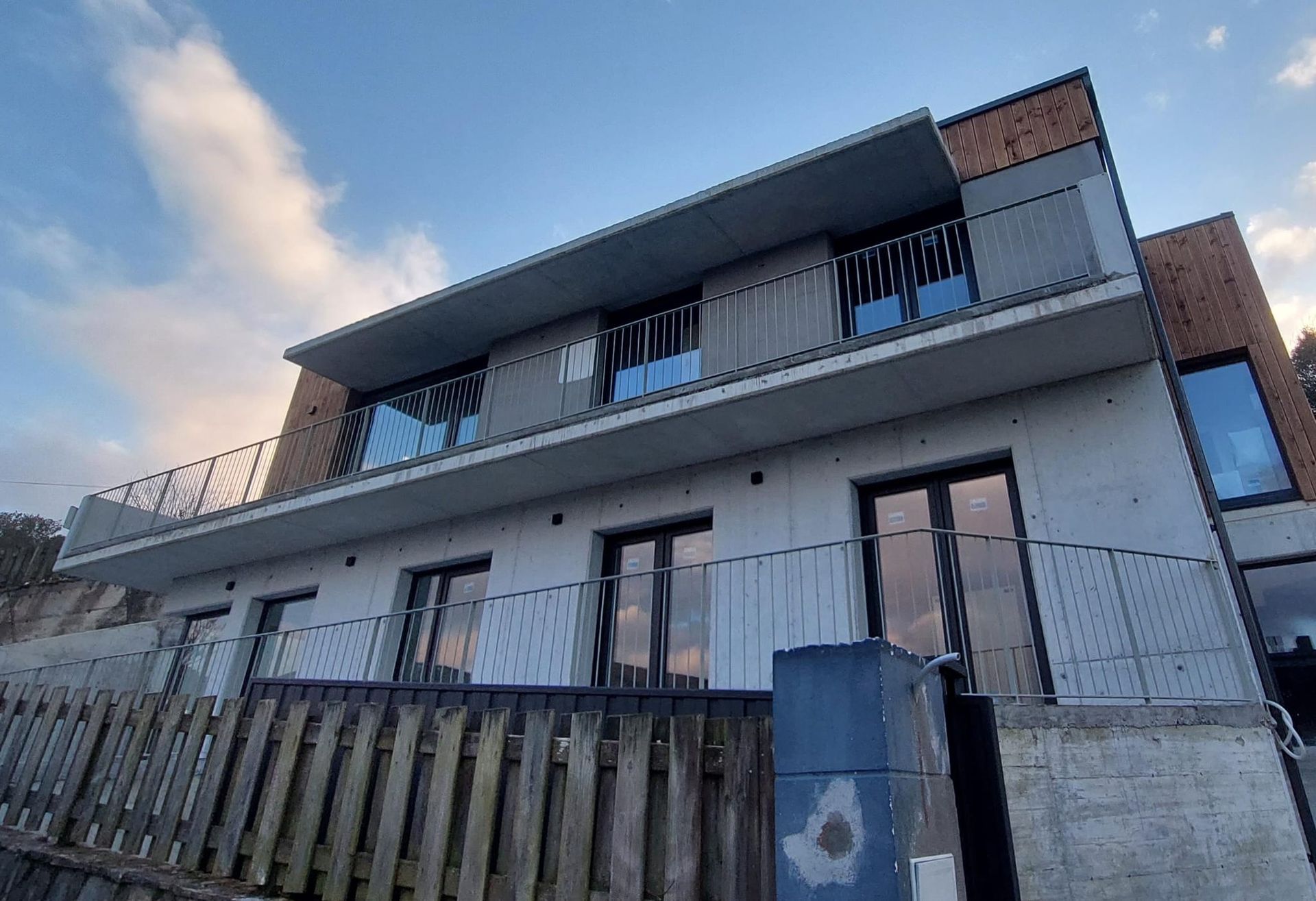 Un edificio grande con un balcón y una valla de madera delante.