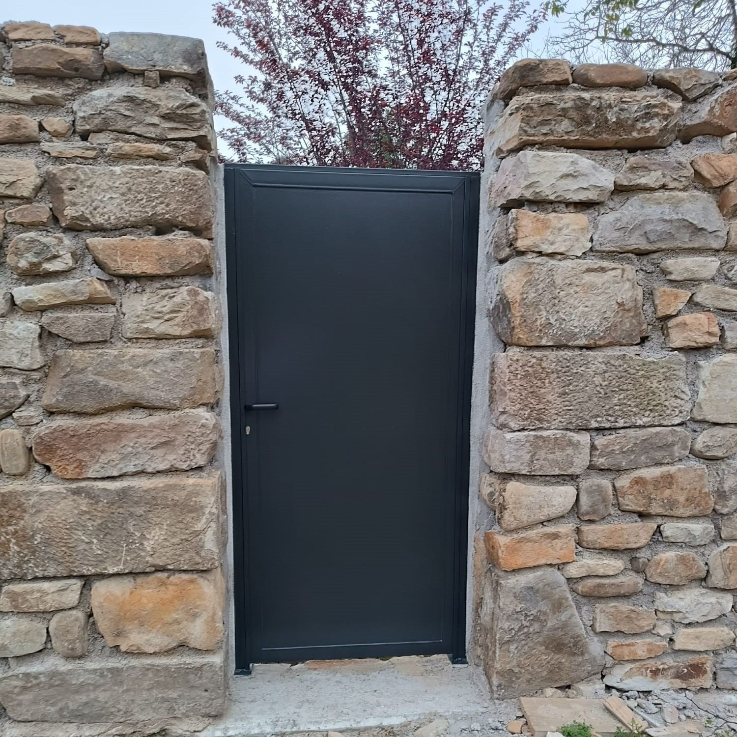 Un muro de piedra con una puerta negra en el medio