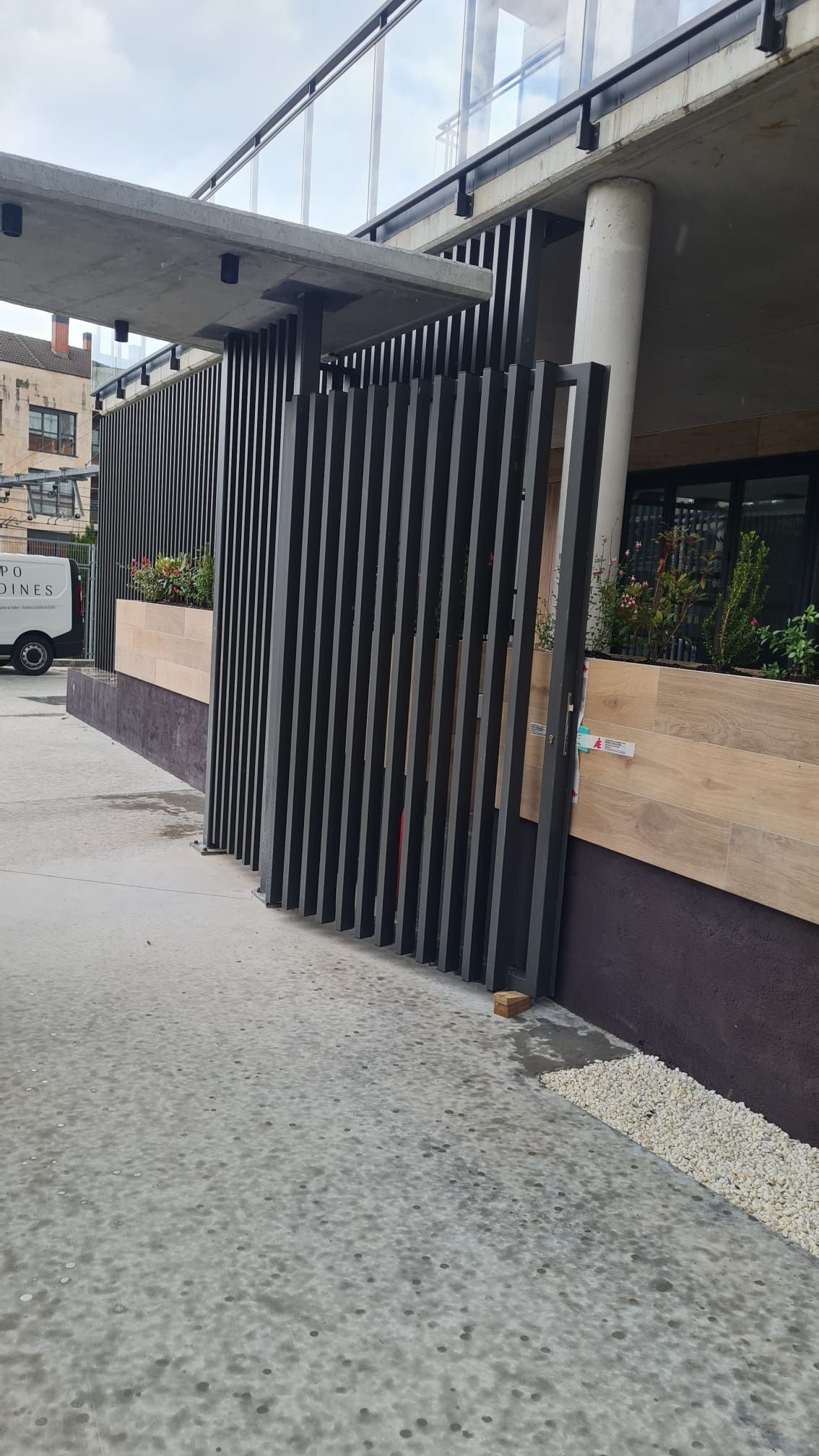 Una camioneta blanca está estacionada frente a un edificio al lado de una valla.
