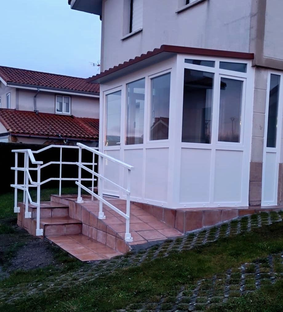 Una casa blanca con una rampa y escaleras que conducen a ella.