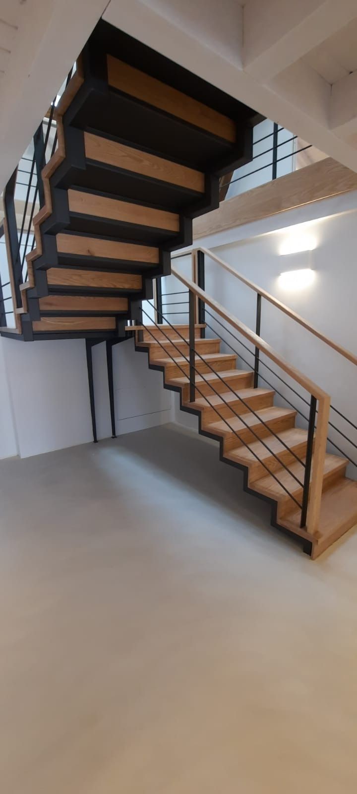 Una escalera de madera con barandilla de metal en una habitación.