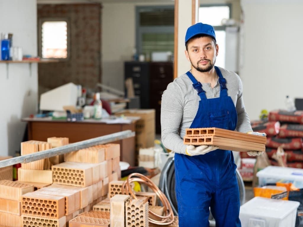 Un hombre sostiene ladrillos en sus manos en un sitio de construcción.