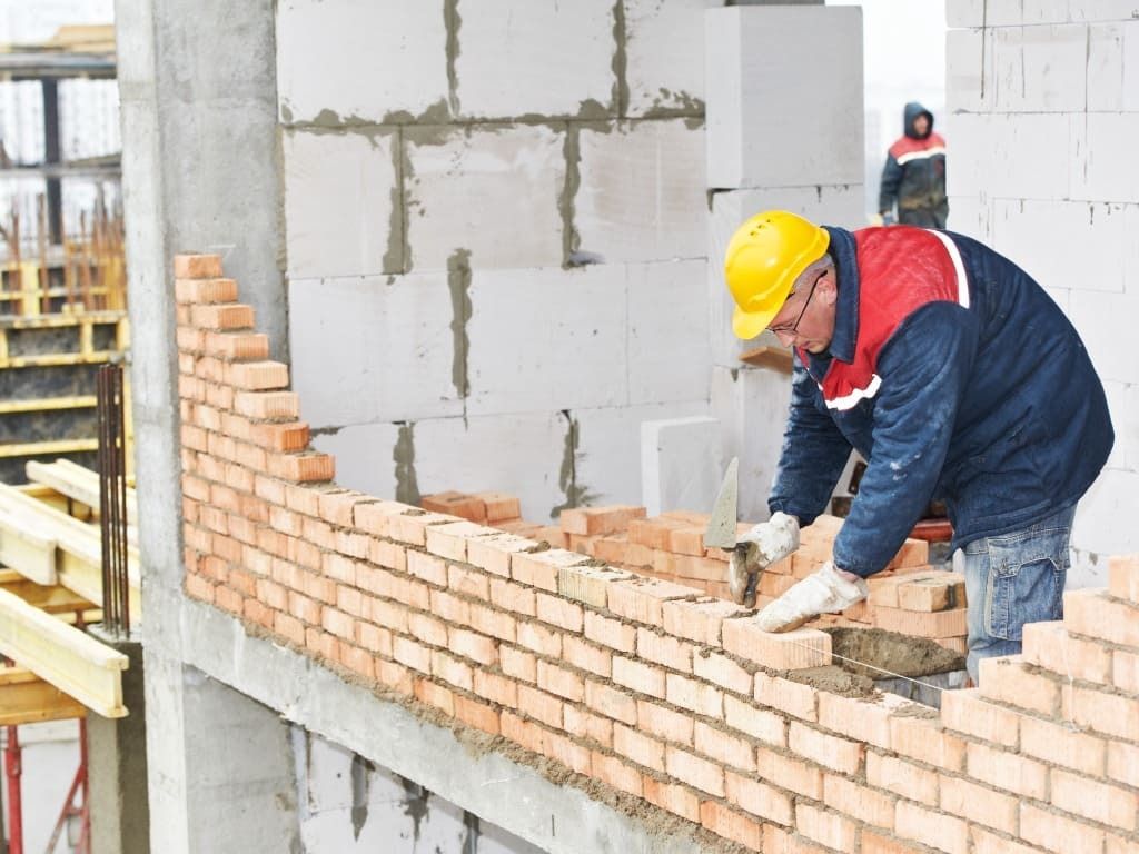 Un trabajador de la construcción está colocando ladrillos en una pared.