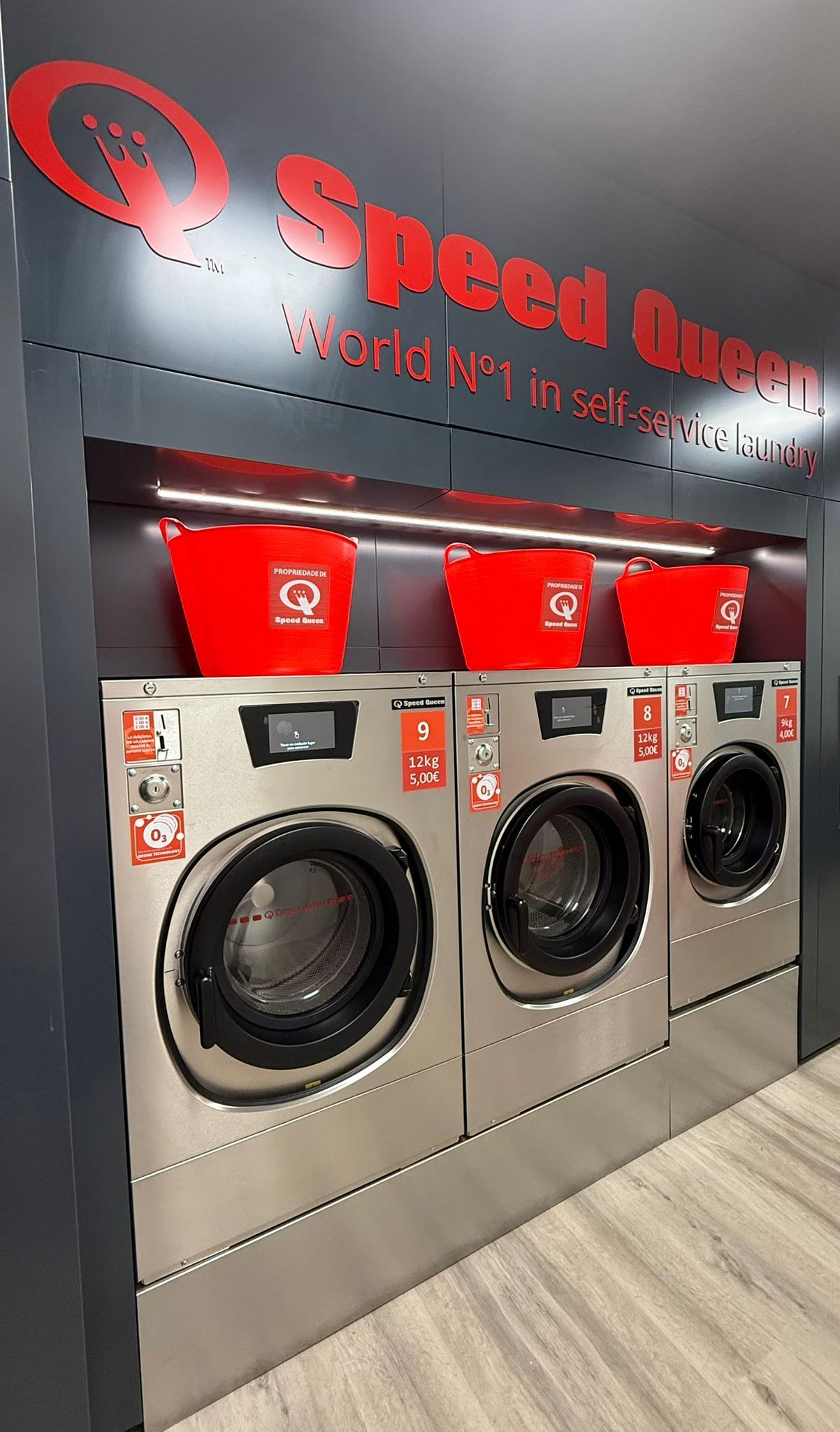 Secadora de ropa comercial de color gris, con panel de control y ranura para monedas.