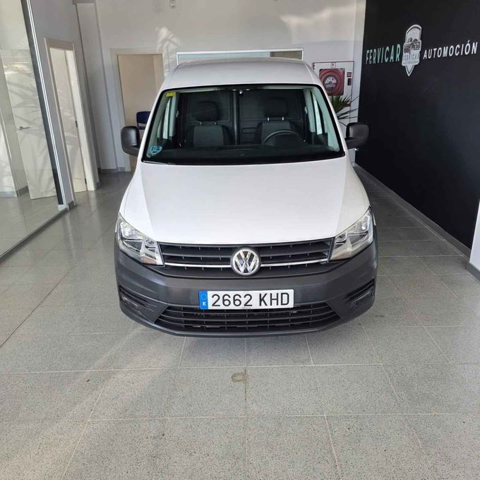 Furgoneta Volkswagen blanca expuesta en el interior de un concesionario, vista frontal, con matrícula 2662 KHD.