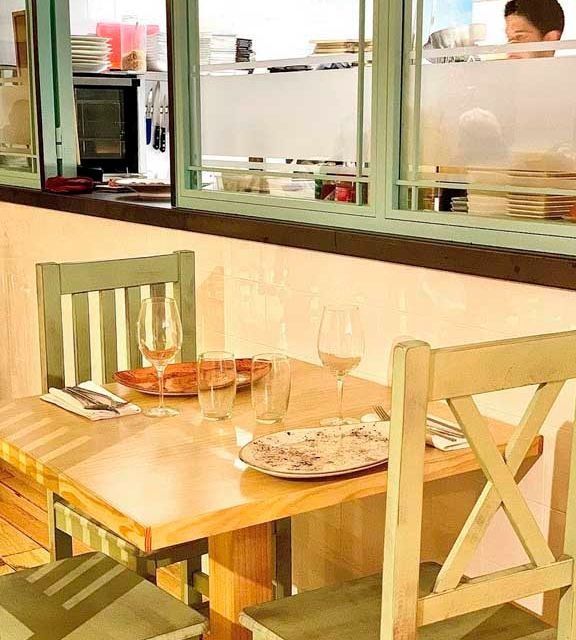 Una mesa de madera con platos y copas de vino encima.