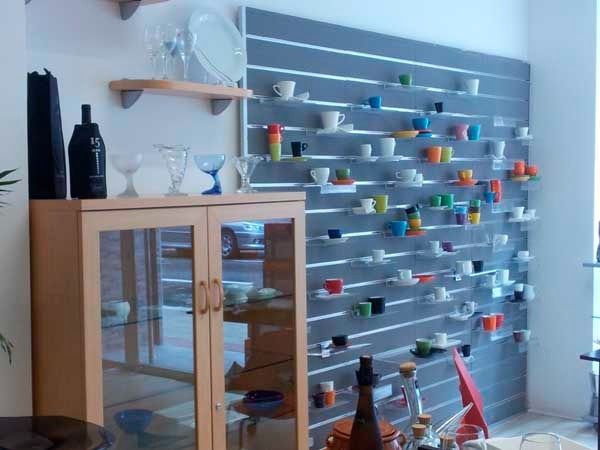 Una sala de estar con una vitrina y una pared con estantes llenos de tazas y platillos.