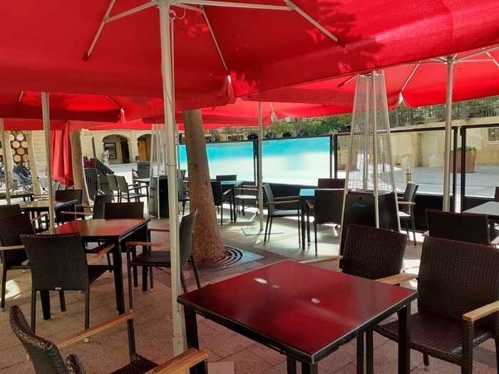 Un restaurante con mesas y sillas bajo sombrillas rojas.