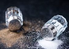 Un salero y pimentero colocado encima de una pila de sal.