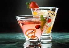 Dos copas de martini llenas de líquido rosa y fresas sobre una mesa.