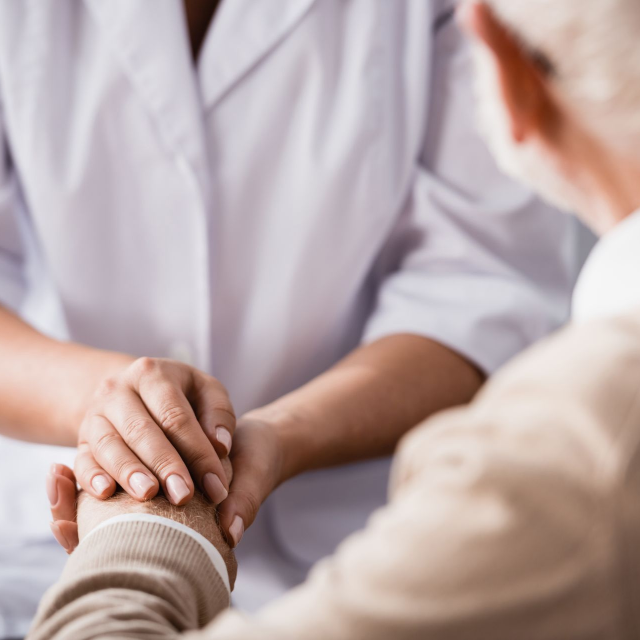 Un médecin tenant la main d'un patient âgé dans un geste réconfortant.