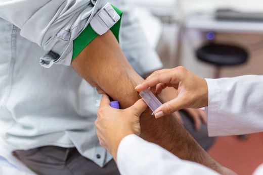 Un infirmier prélève du sang au bras d'un patient à l'aide d'une seringue.