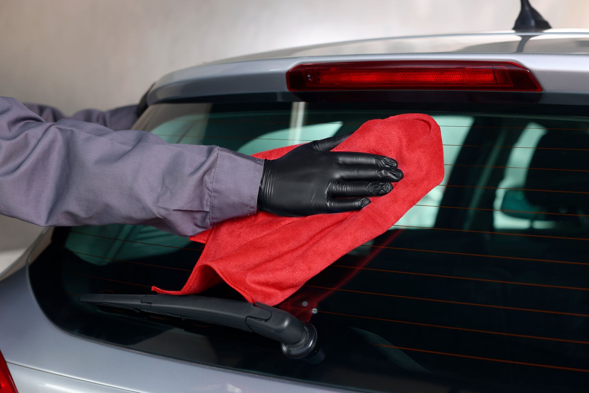Un professionnel qui essui une lunette arrière de voiture