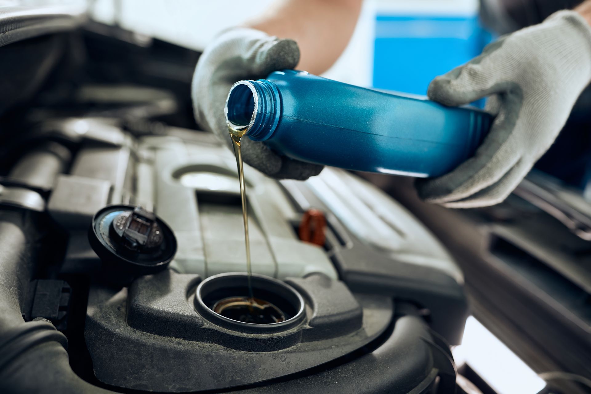 Un professionnel qui verse de l'huile dans un moteur de voiture