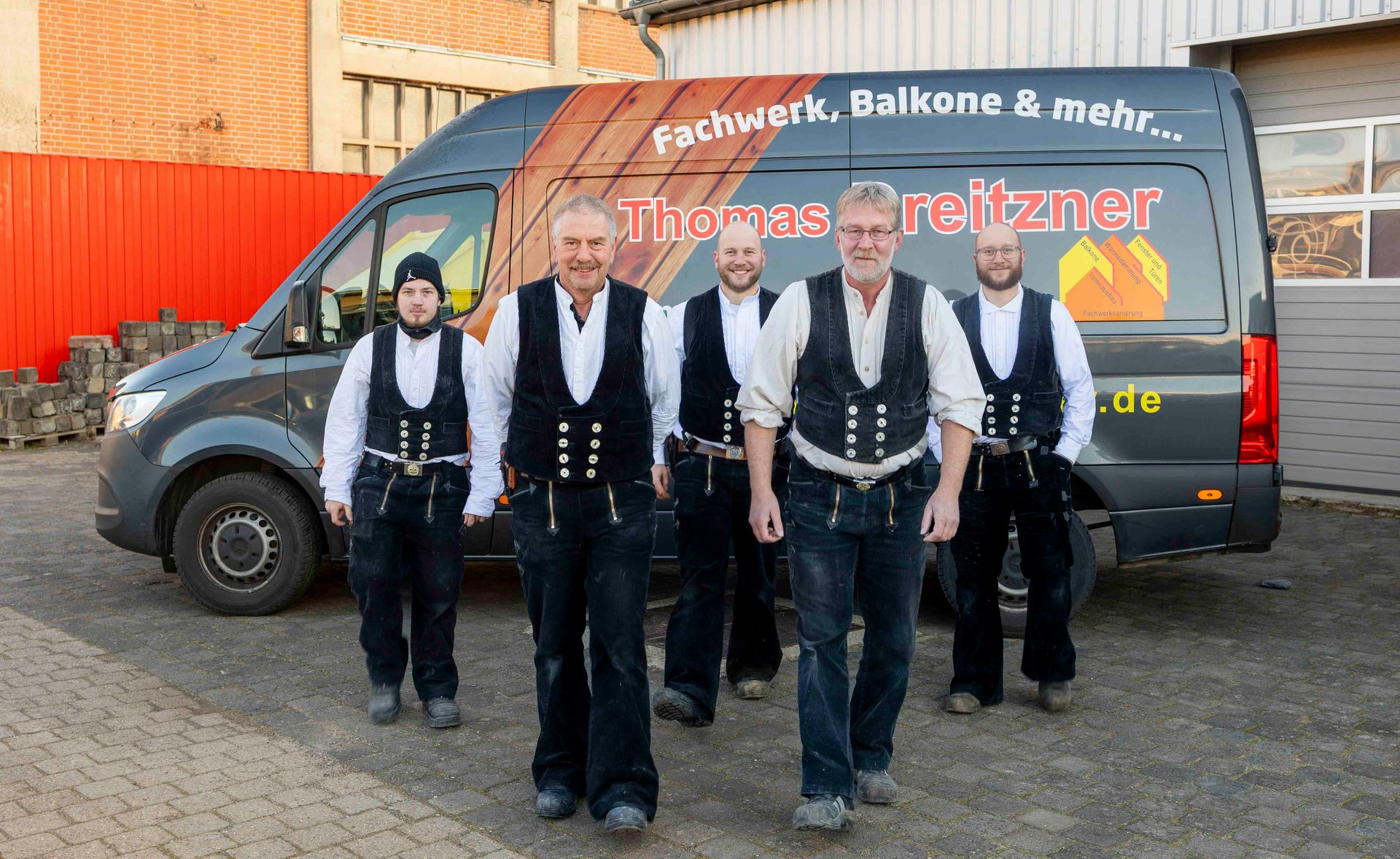 Fünf Bauarbeiter stehen vor einem Lieferwagen, sie tragen Westen und Werkzeuggürtel.