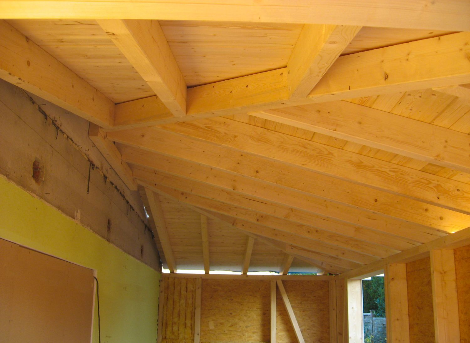 Holzkonstruktion des Dachstuhls im Inneren eines Gebäudes, wobei Sparren und Balken sichtbar sind.