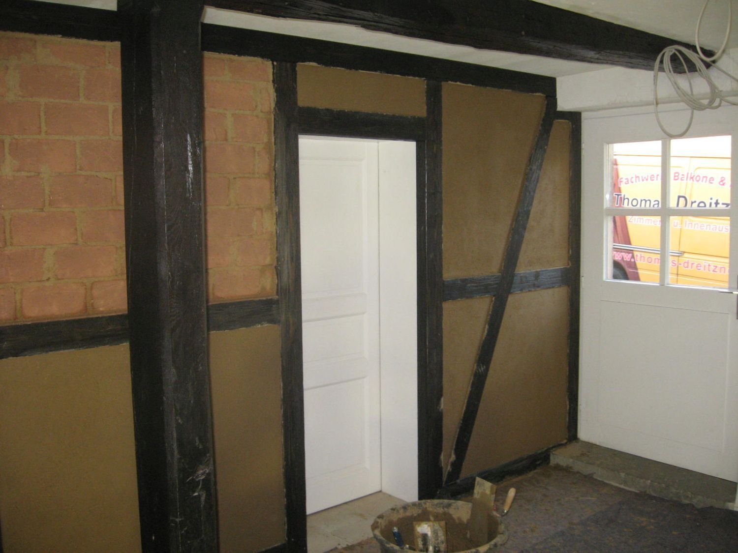 Innenwand im Bau, freiliegendes Fachwerk, Ziegel und Putz.