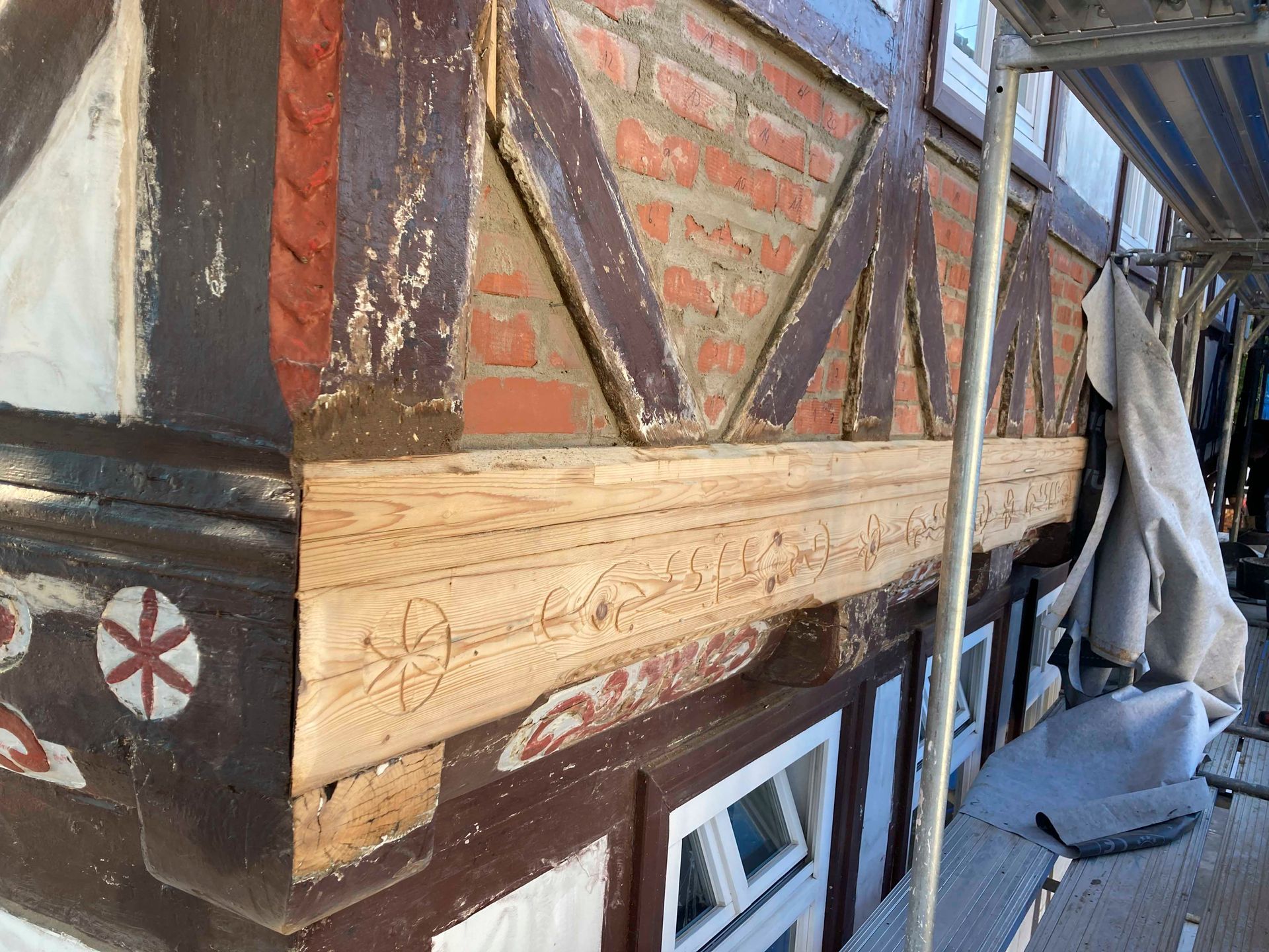 Nahaufnahme eines Fachwerkhauses. Die verwitterten Holzbalken und die rote Ziegelsteinfüllung sind erkennbar.