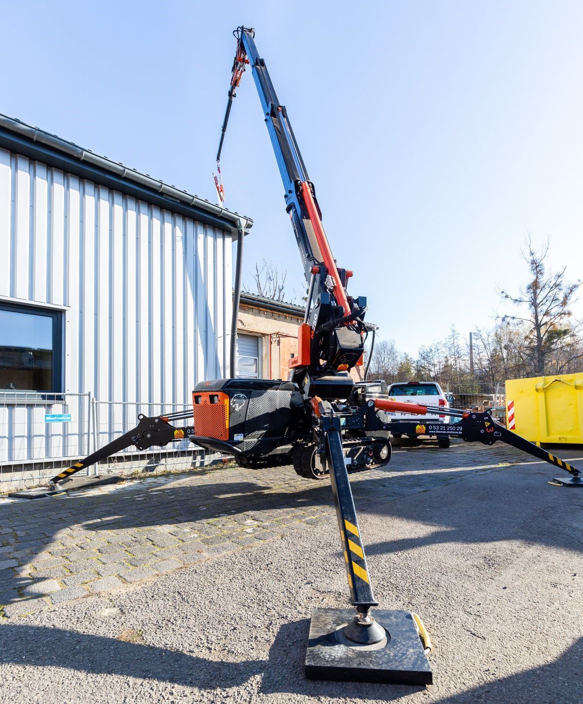 Ein Spinnenkran wurde in der Nähe eines Gebäudes ausgefahren, seine Stützbeine waren bereits angebracht.