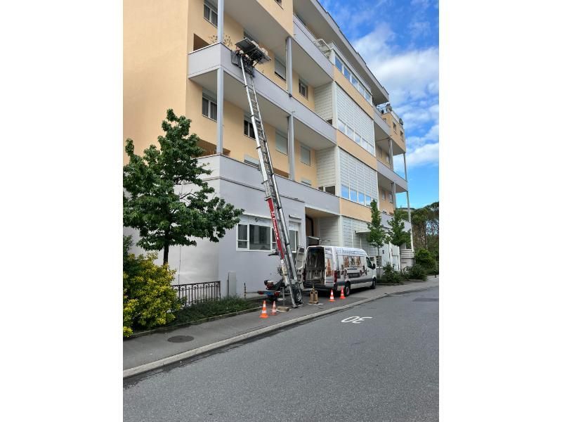 Une camionnette est garée devant un bâtiment avec une échelle attachée dessus.