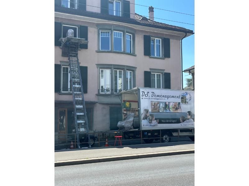 Un camion est garé devant un bâtiment avec une échelle attachée dessus.