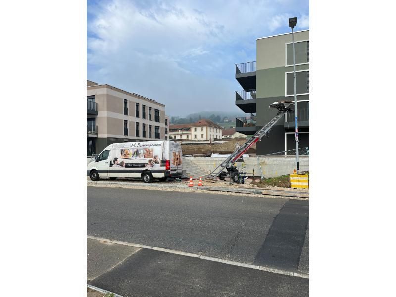 Une camionnette blanche est garée sur le bord de la route devant un bâtiment.