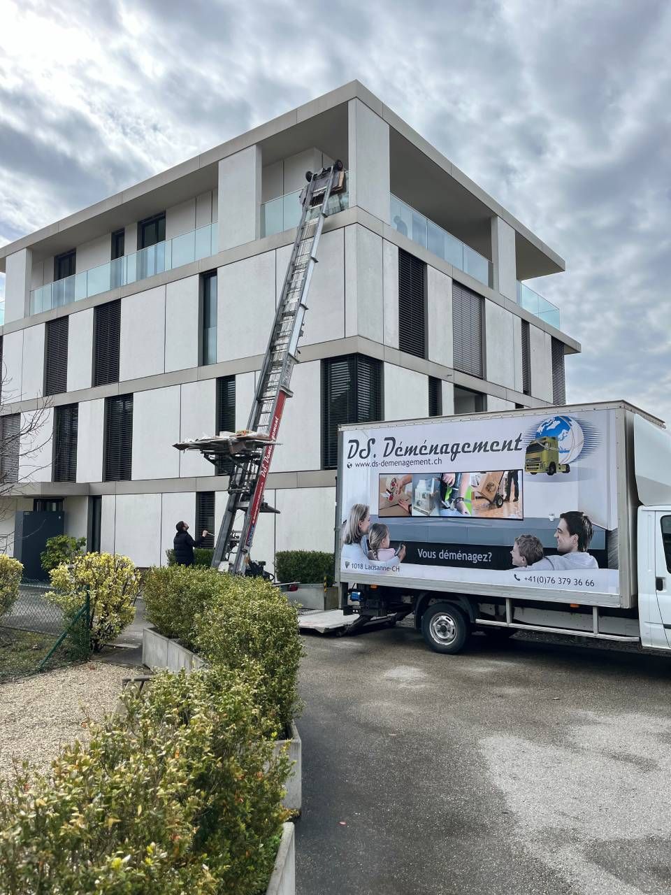 Un camion blanc est garé devant un grand bâtiment