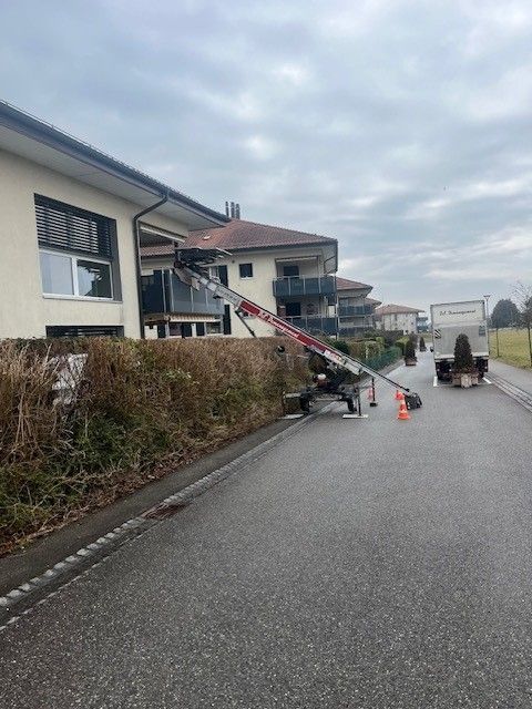 Un camion est garé devant un bâtiment avec une échelle attachée dessus.