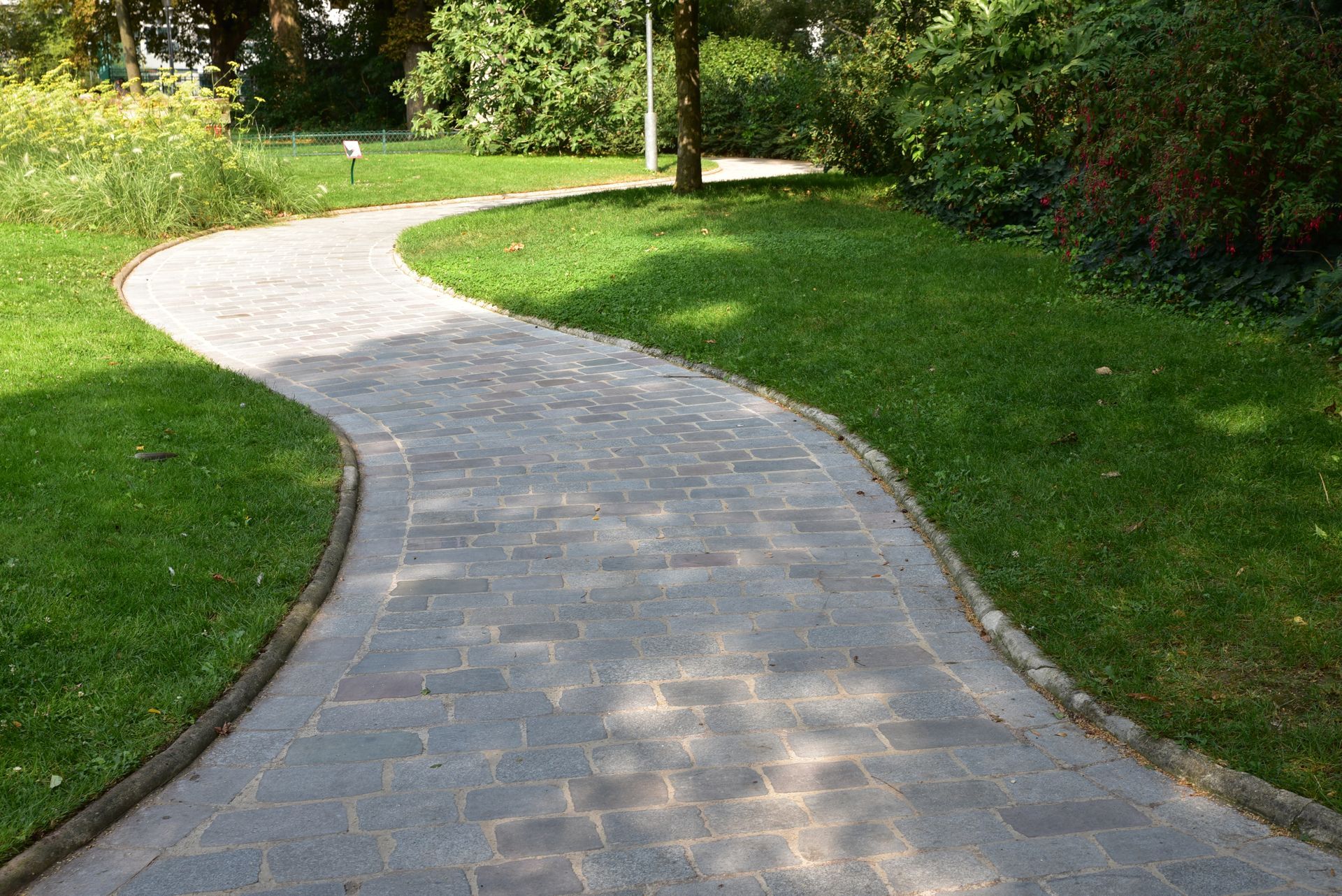 Allée de jardin en pavés traversant une pelouse bien entretenue