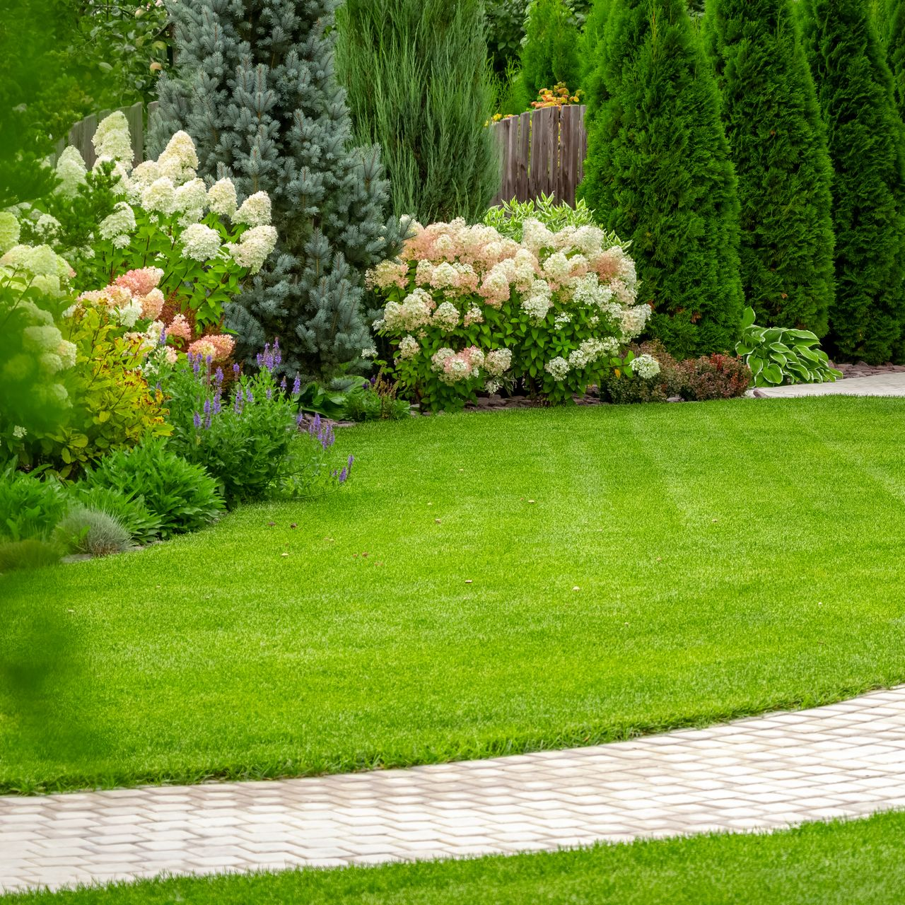 Jardin paysager avec arbres, arbustes et parterres fleuris
