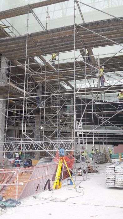 Se está construyendo un gran edificio con andamios y obreros.