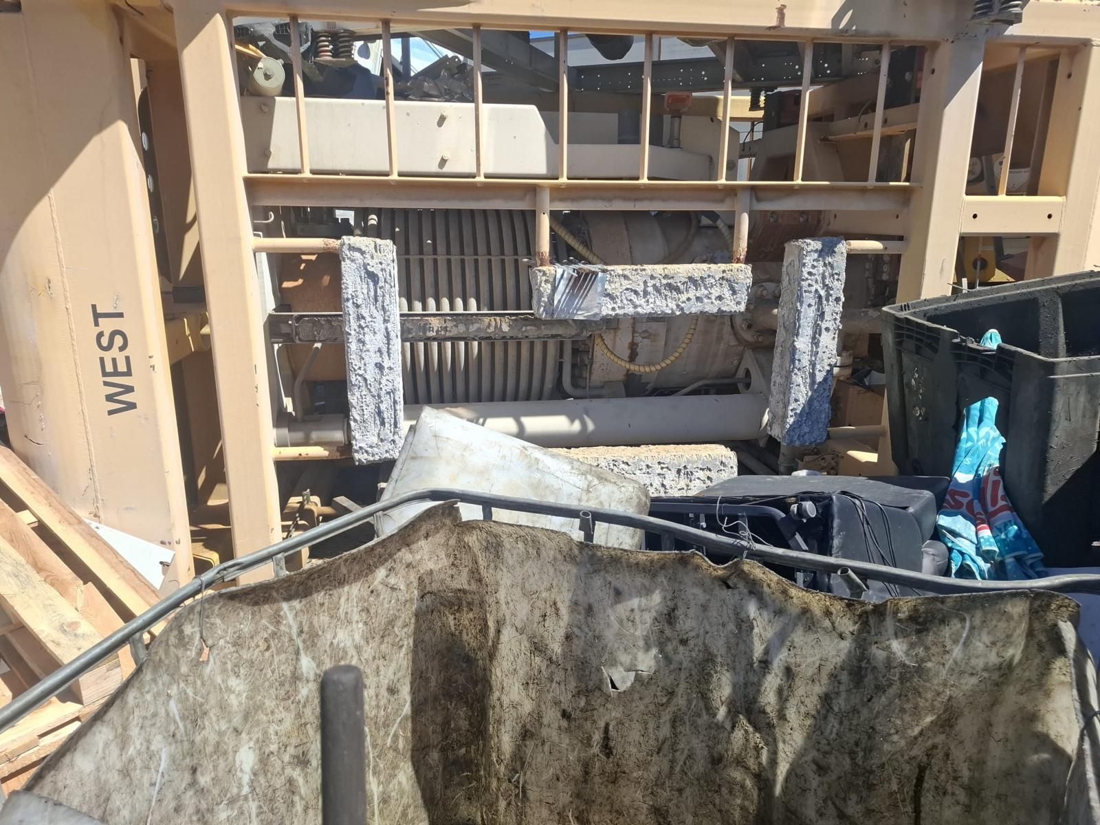 Trabajador operando una fregadora de suelos en una gran instalación interior con suelo de hormigón mojado.