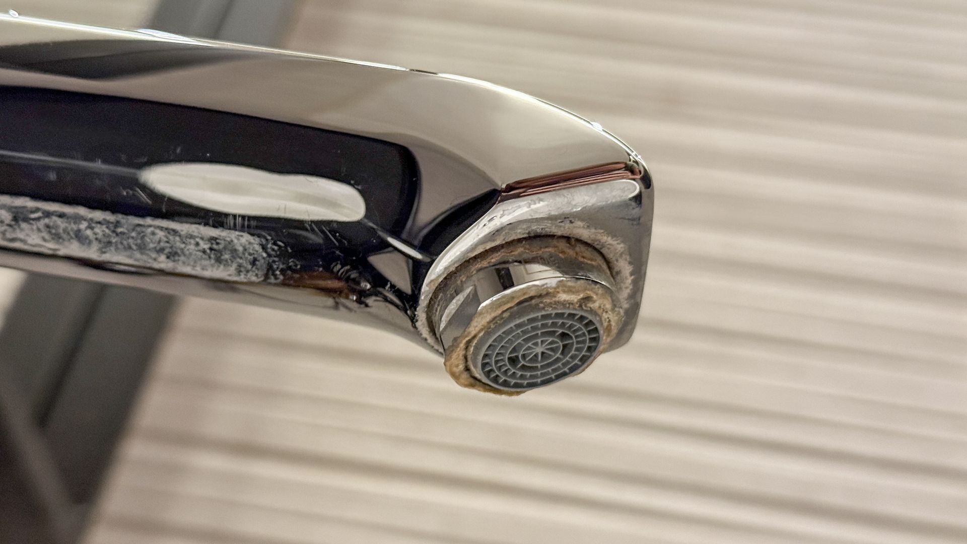 Robinet chromé avec accumulation de minéraux autour de l'aérateur et de la base.